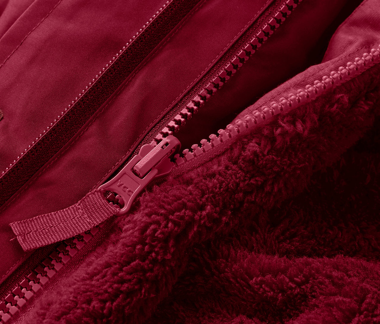 Egy piros, 3 az 1-ben gyermek télikabát részlete cipzárral.