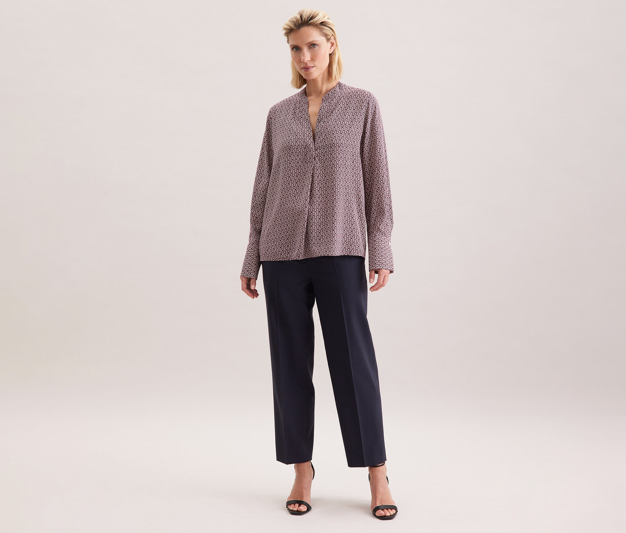 Nő visel egy ekrü-bordó mintás Seidensticker viszkóz tunikát, sötét nadrággal és fekete szandállal kombinálva.