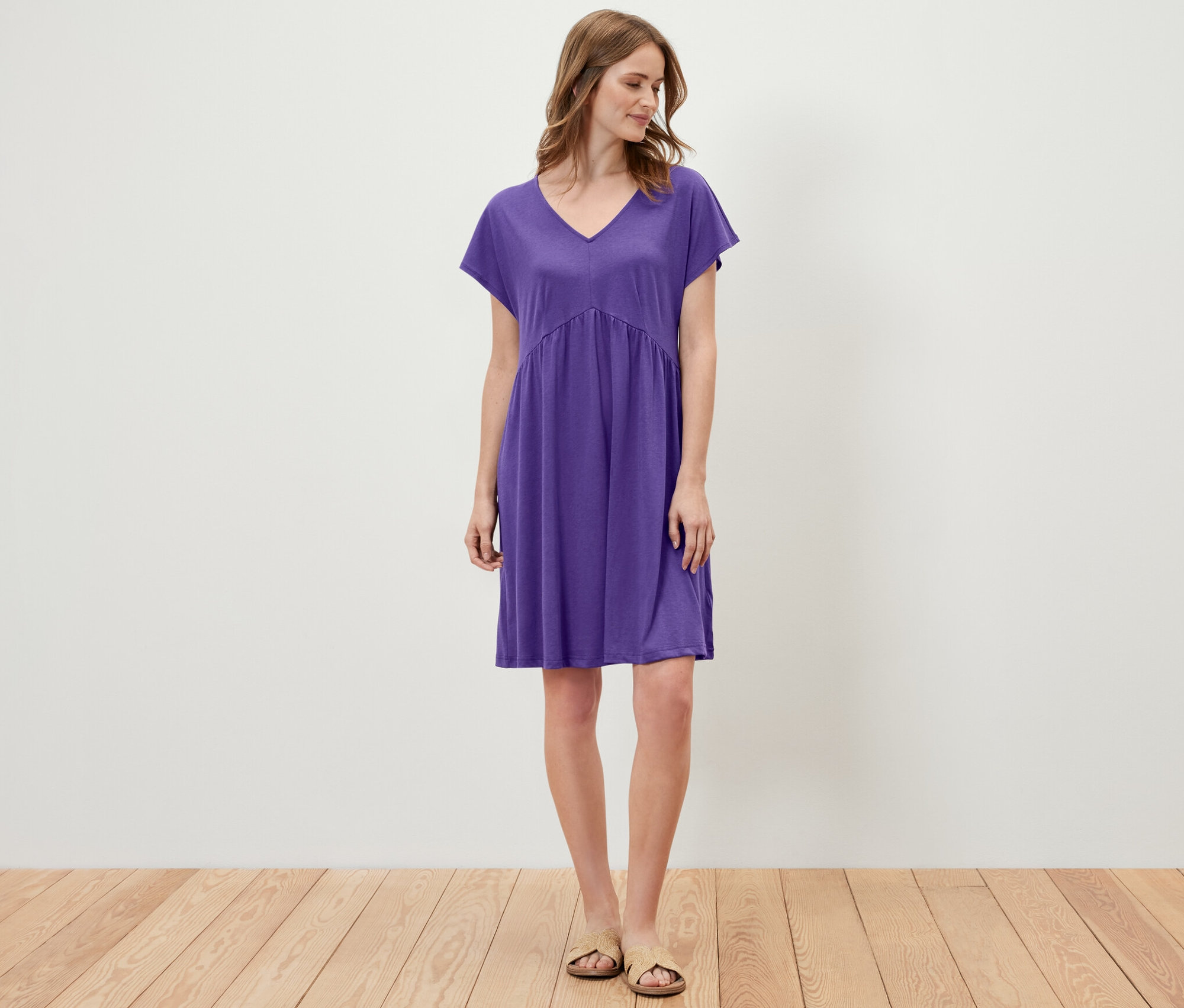 Egy nő áll egy lila jerseyruhában.
