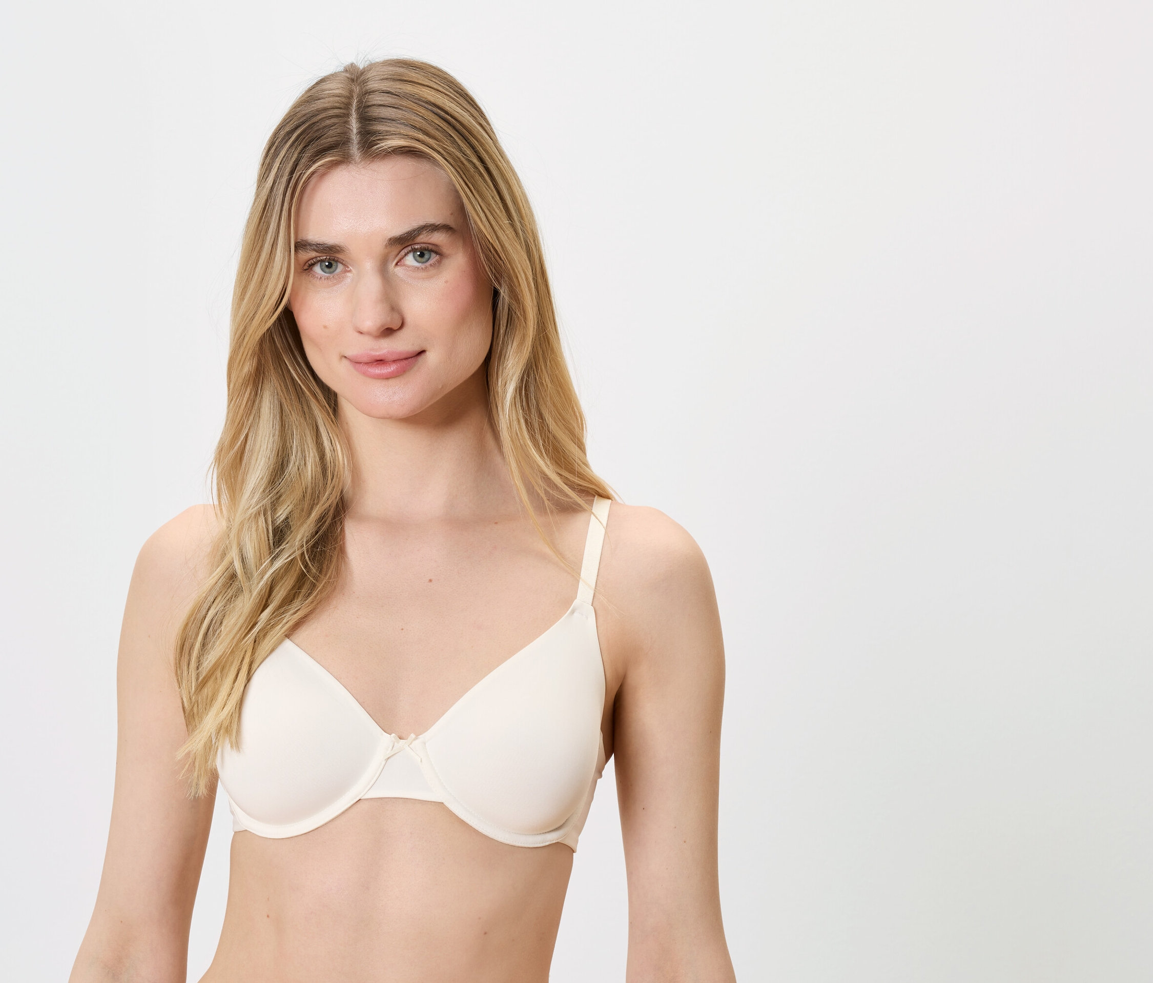 Szőke, kék szemű nő testszínű melltartót visel.