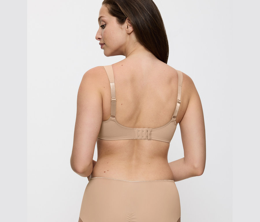 Hátulnézet egy testszínű Triumph Essential »Minimizer W X« melltartót viselő nőről.