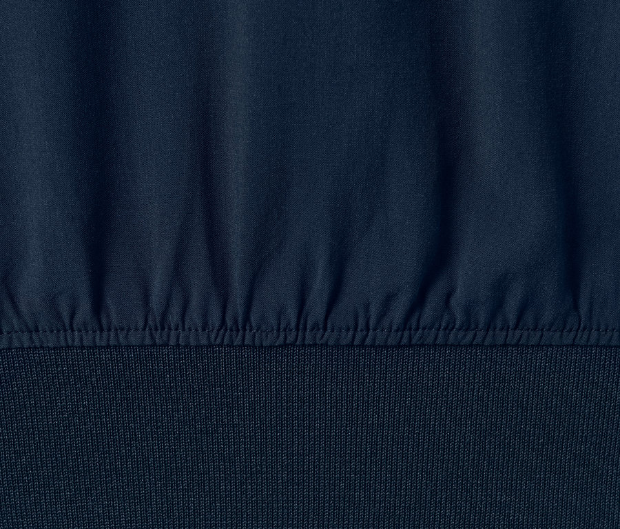 Sötétkék, bordázott szegélyű női blúz részlete.