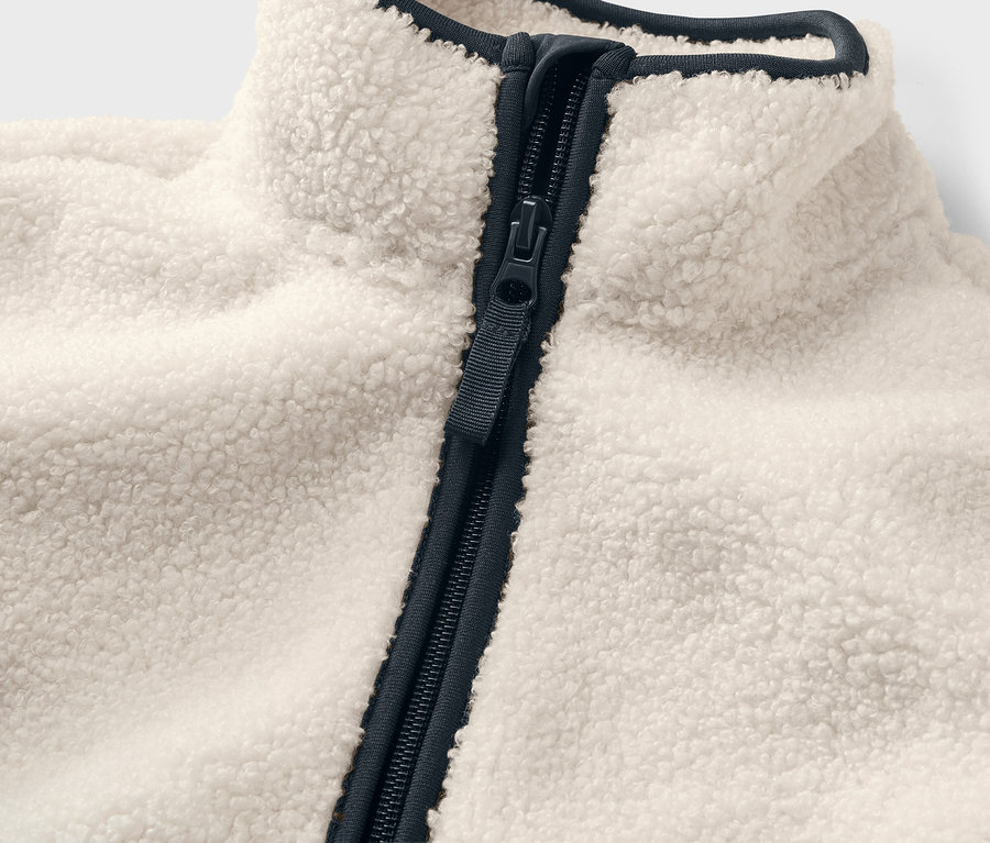 Egy gyerek plüsskabát részlete sötétkék cipzárral és szegéllyel.