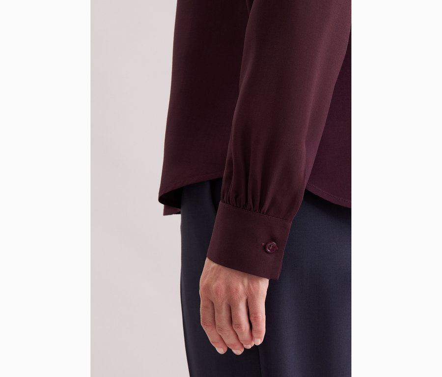 Egy nő közeli képe, aki Seidensticker viszkóz sifon blúzt visel.