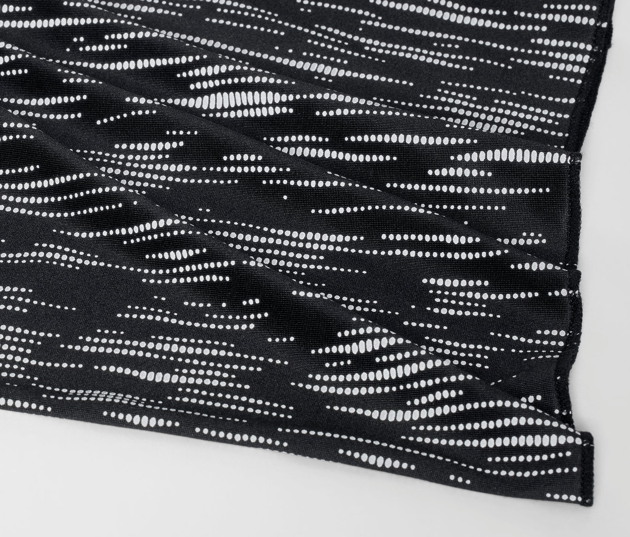 Egy fekete szövetborító részlete fehér pöttyös mintával.