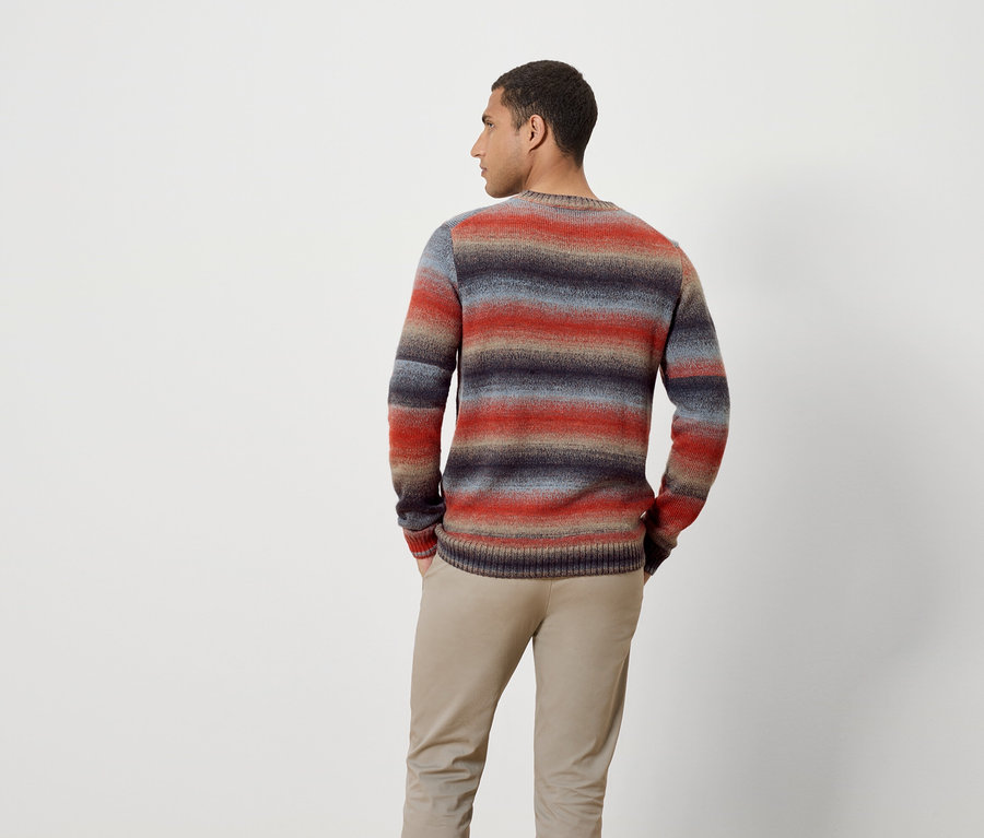 A fényképezőgépnek háttal álló férfi csíkos pulóvert és nadrágot visel.