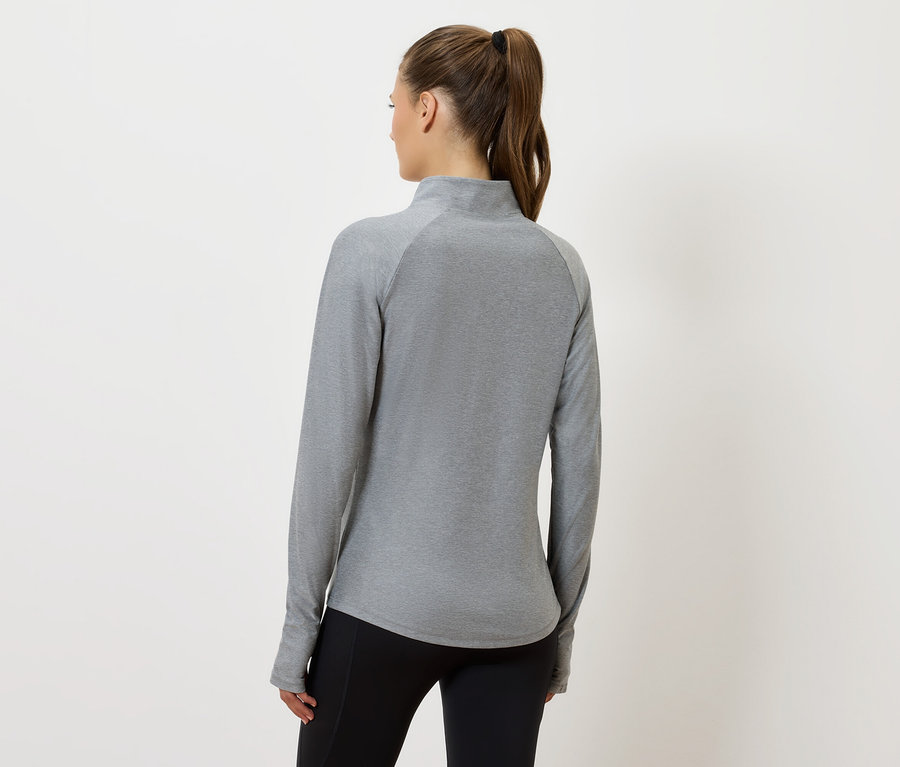 A kamera felé háttal álló nő szürke, hosszú ujjú felsőt és fekete nadrágot visel.