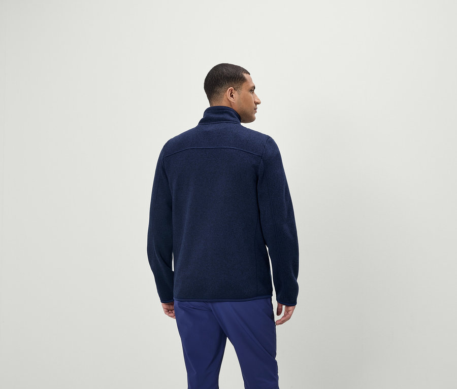 Férfi kék cipzáras pulóvert és kék nadrágot visel.