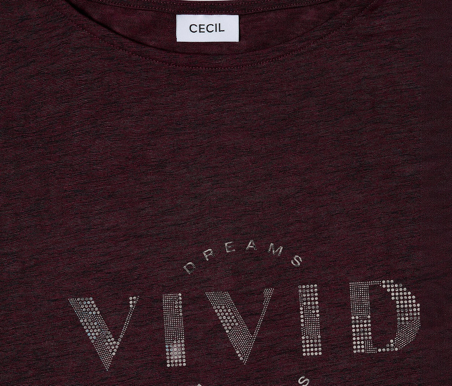 Egy bordó CECIL póló közeli képe, ezüst színű strasszkövekkel kirakott "VIVID DREAMS" felirattal.