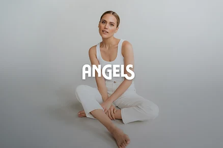 Egy nő ül a földön, fehér atlétában és fehér nadrágban, keresztbe tett lábakkal, a kamerába néz. Az "ANGELS" felirat rá van helyezve.
