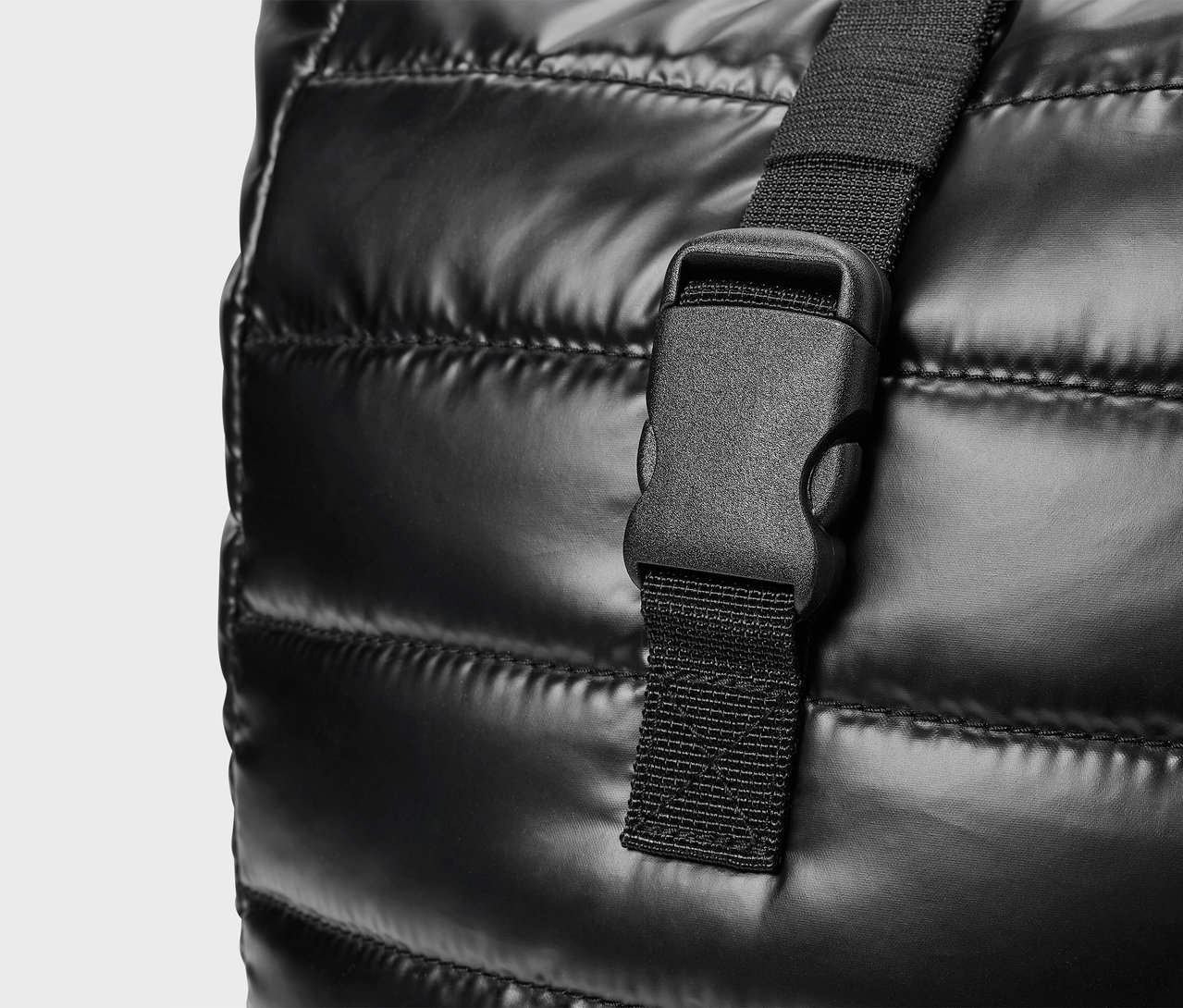 Egy fekete, steppelt táska részlete, műanyag csattal.