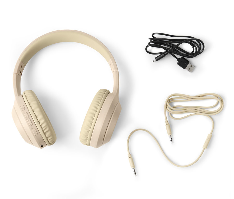 Egy bézs színű Bluetooth fejhallgató és két kábel fehér háttér előtt.