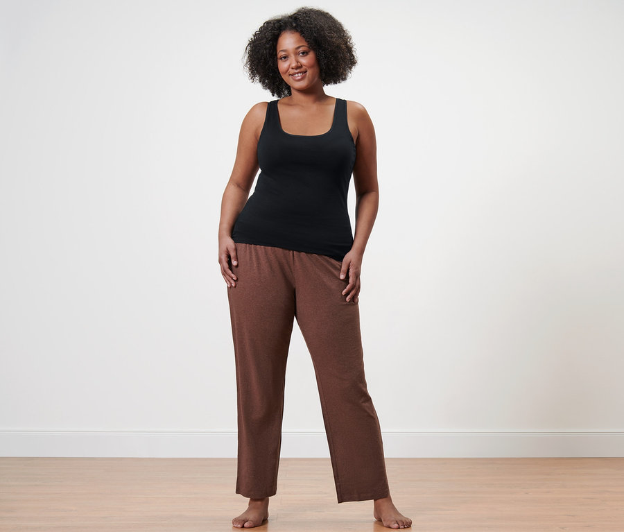 Egy nő pizsamanadrágot és egy fekete trikót visel.