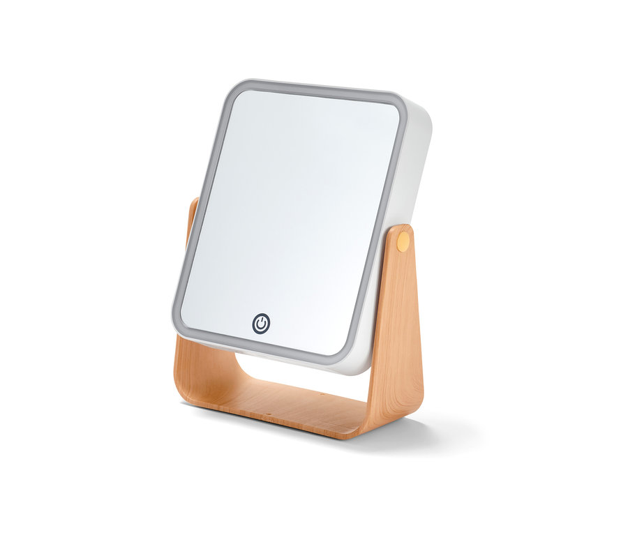 Egy LED-es kozmetikai tükör közeli képe fa állványon.