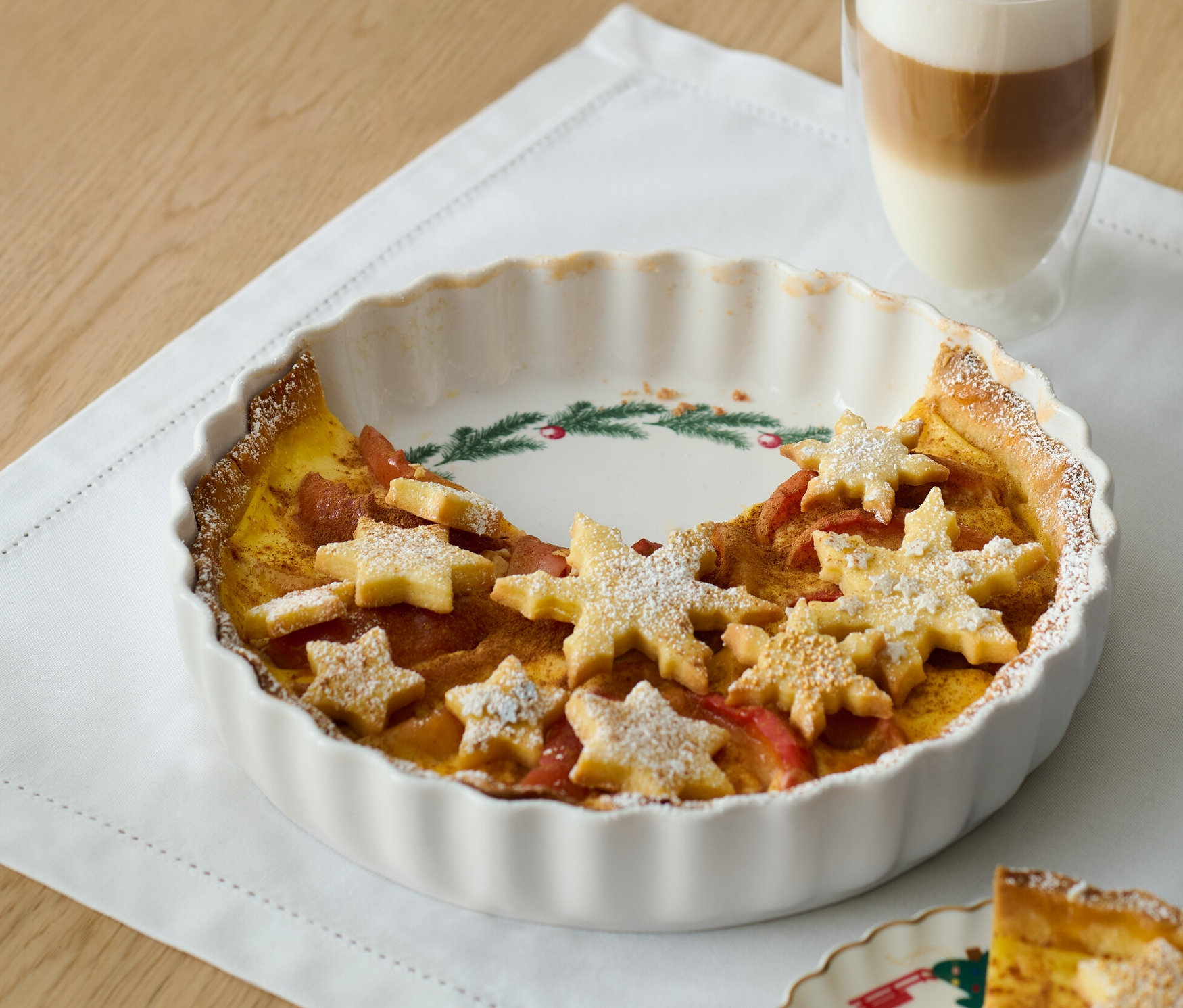 Torta porcelán piteformában tészta csillagokkal és egy pohár latté.