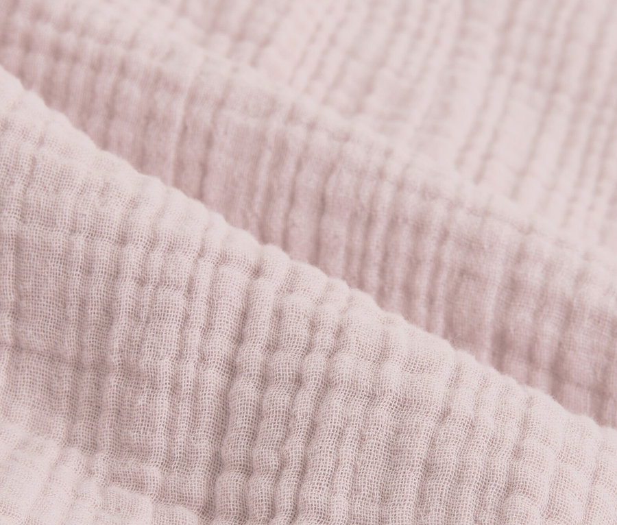 Közelkép a rózsaszín muszlin ágyneműről.