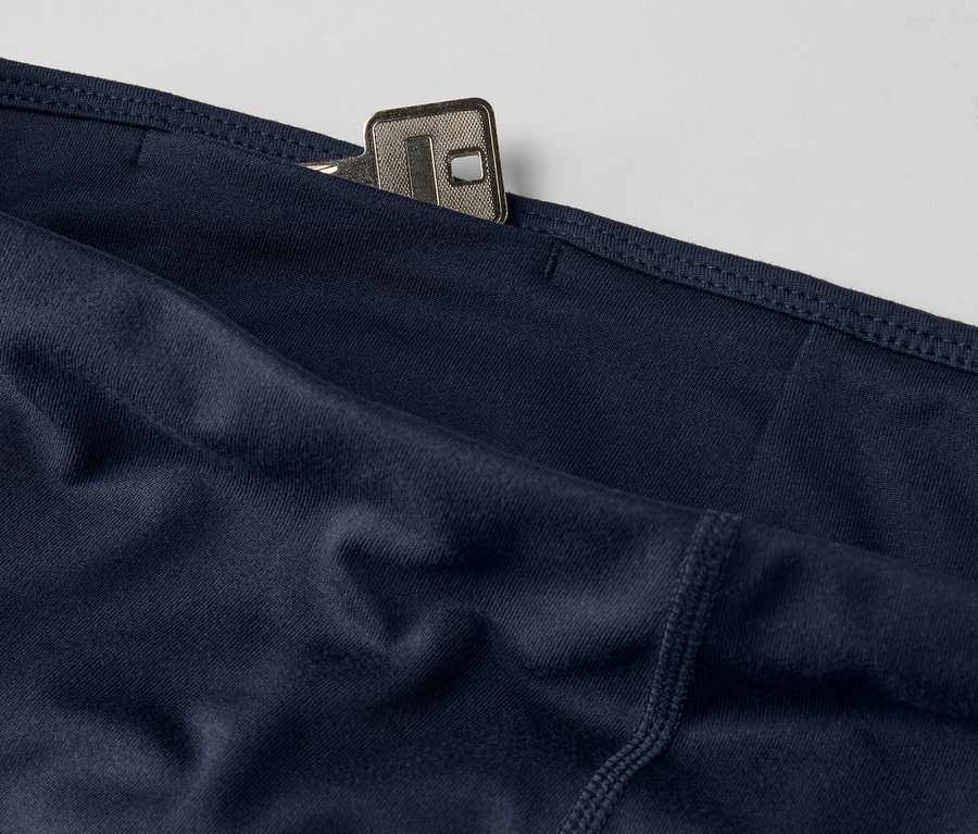 Egy sötétkék, 3/4-es sportnadrág részlete, zsebben egy kulccsal.