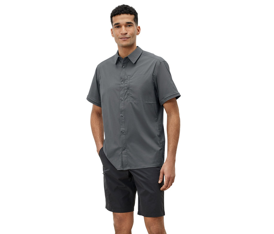 Egy férfi szürke túraingben és fekete rövidnadrágban pózol.