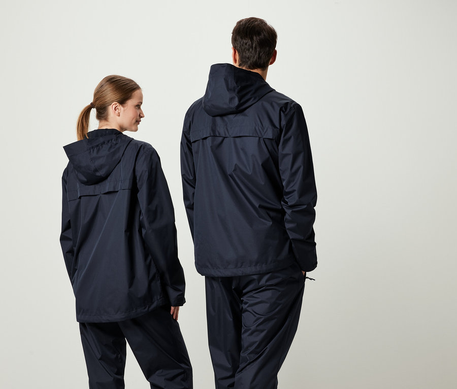 Két ember háttal a kamerának, sötétkék kapucnis kabátban és nadrágban.
