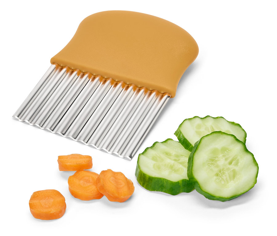 Hullámos zöldségszeletelő narancssárga fogantyúval, vágott uborka és sárgarépa mellett.