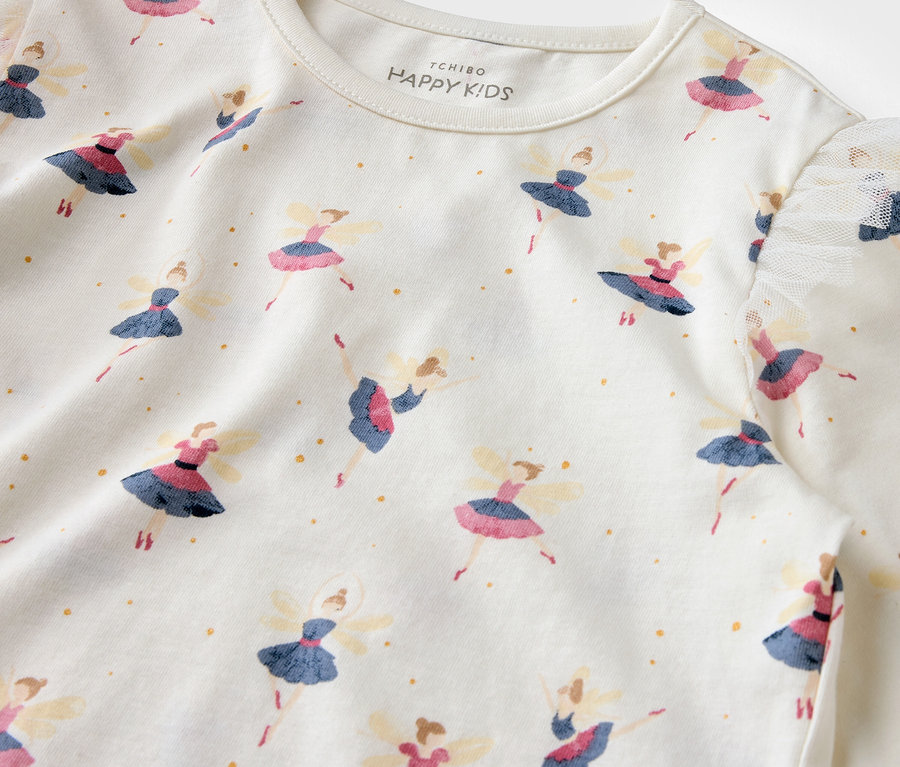 Egy fehér póló részlete, balerina mintával és arany pöttyökkel.