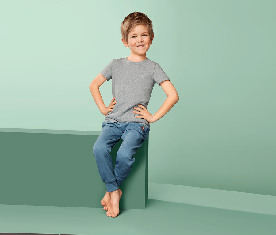 Egy fiú ül egy zöld tömbön és 2 kisfiú pólót visel.