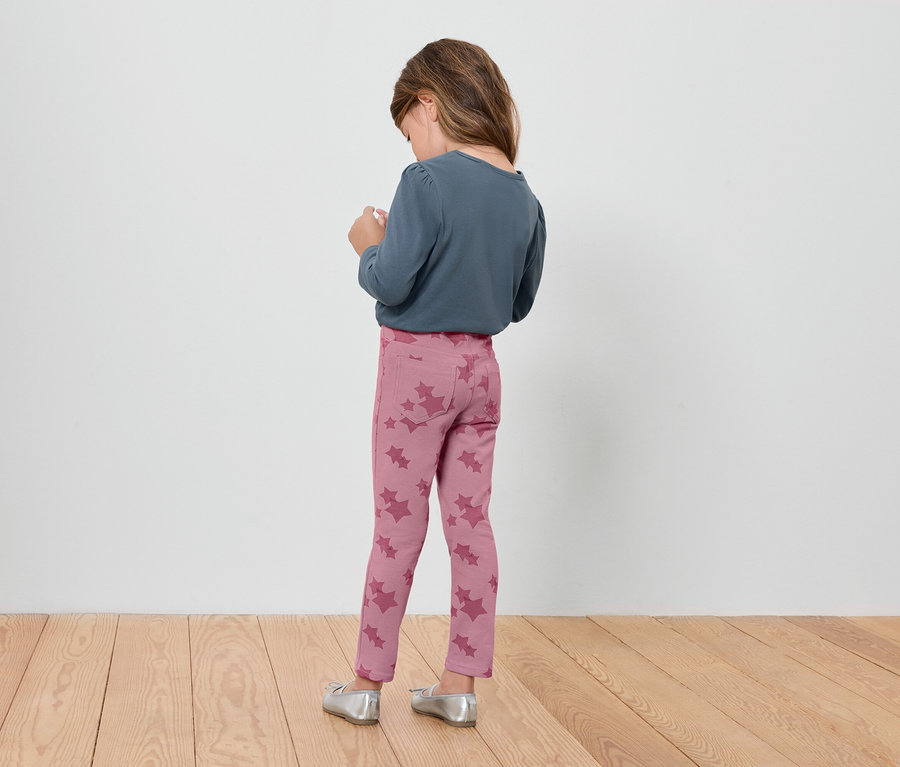 Virágmintás rózsaszín leggingset és kék hosszú ujjú felsőt viselő lány háttal áll.