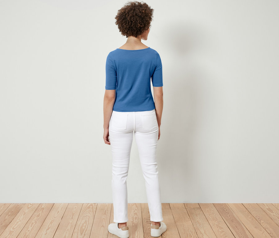 Egy nő háttal áll a kamerának, kék, félhosszú ujjú felsőt visel.