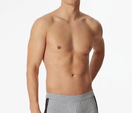 Férfi áll félmeztelenül, világosszürke, melírozott SCHIESSER boxeralsót visel, oldalán fekete csíkkal.