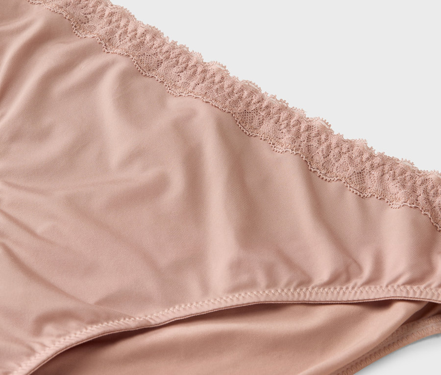 Egy világos rózsaszín, csipkével díszített alsónemű közeli képe.