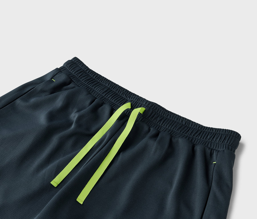 Egy sötétszürke rövidnadrág közeli képe, világoszöld húzózsinórral.