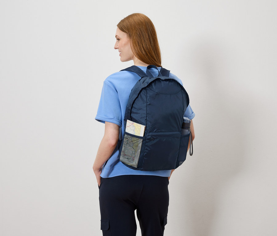 Hátulról egy nő látható sötétkék hátizsákkal, amiben térkép és vizes palack van.