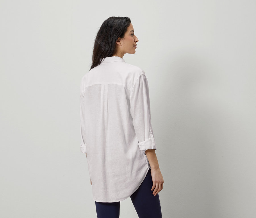 Nő hátulról fehér ingben és kék leggingsben.