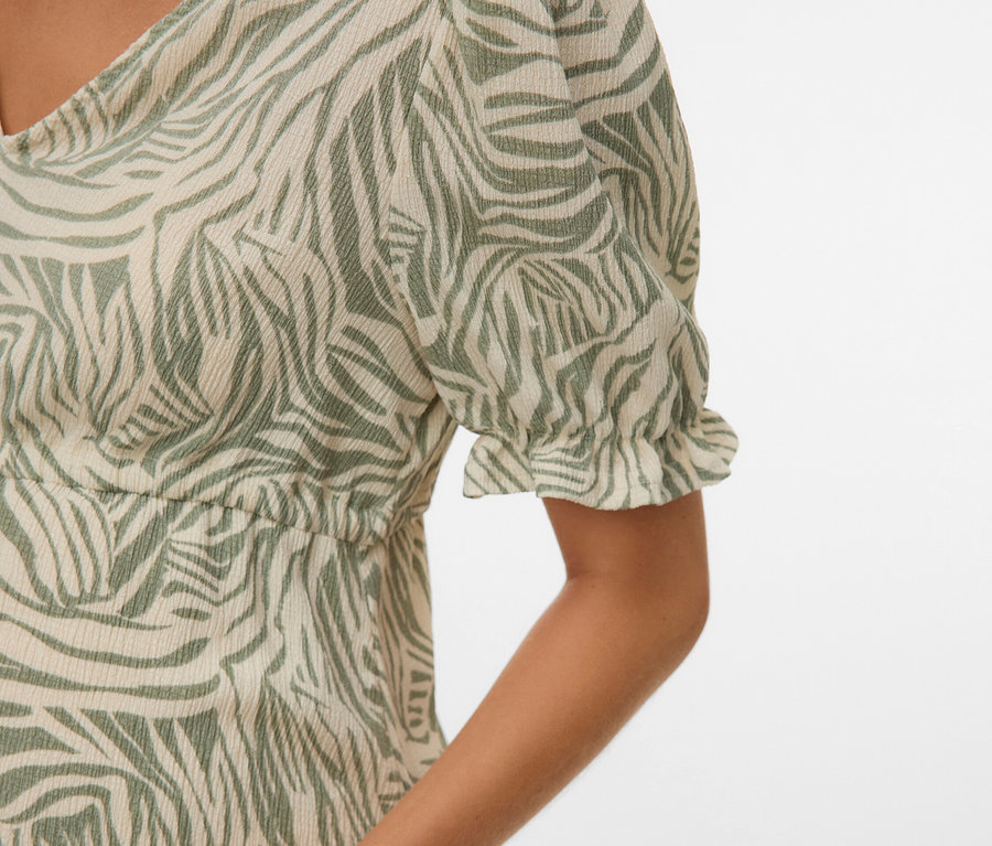 Közelkép egy zöld zebracsíkos ruhát viselő nőről.