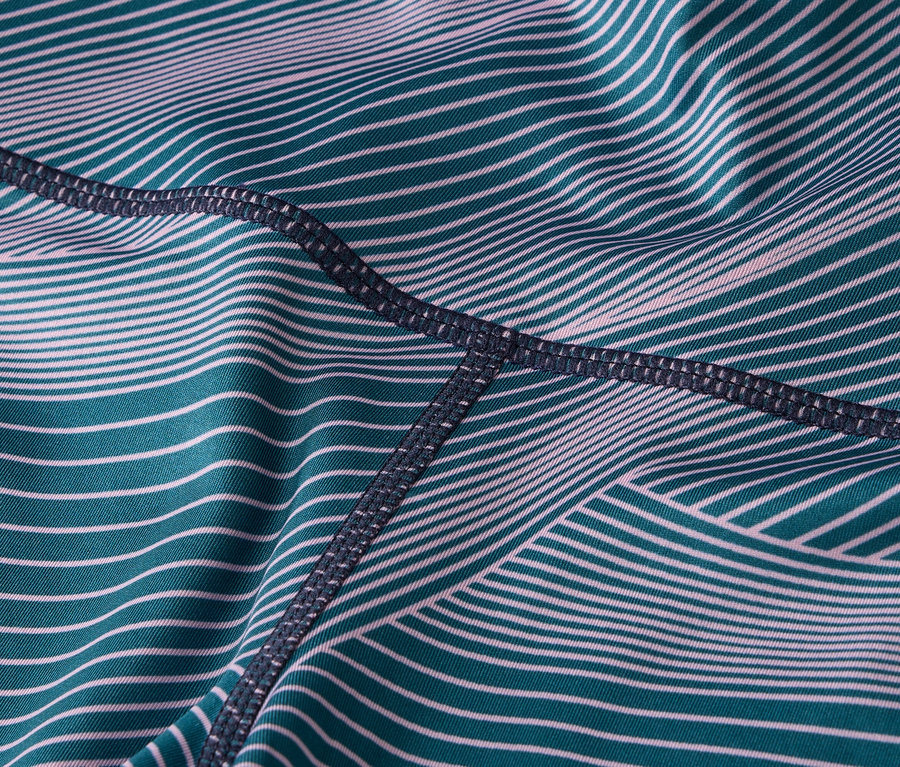 Közelkép a türkiz és fehér csíkos, sötét varrású leggings anyagáról.