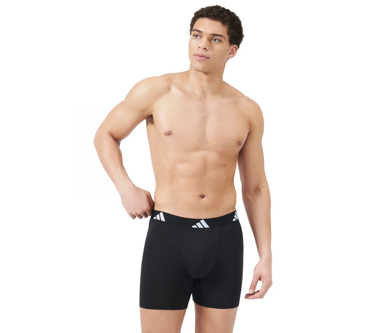 Felsőtestén meztelen férfi fekete boxeralsót visel fehér adidas logós derékpánttal, jobbra néz, bal kezét a derékpánton tartja.