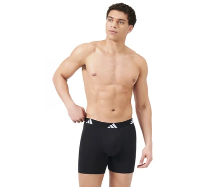 Felsőtestén meztelen férfi fekete boxeralsót visel fehér adidas logós derékpánttal, jobbra néz, bal kezét a derékpánton tartja.