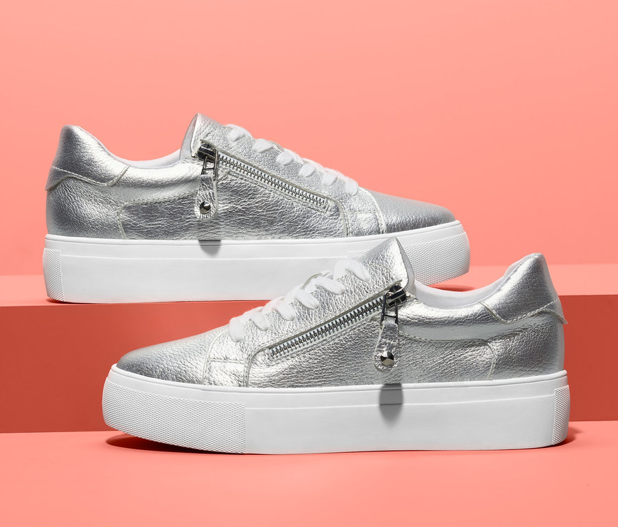 Két ezüst színű, bőr női sneaker cipő fehér platformtal.