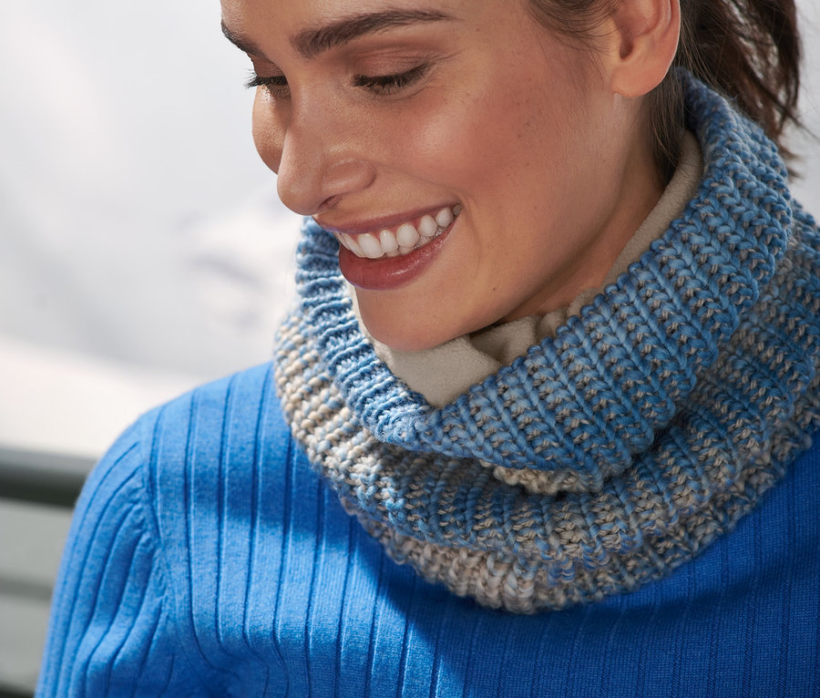Mosolygó nő kötött csősálat visel a nyakában.