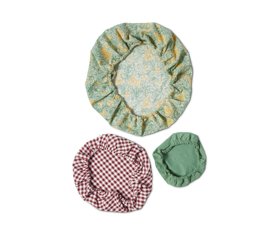 Három textil frissentartó fedél: egy zöld virágmintás, egy piros kockás és egy zöld.
