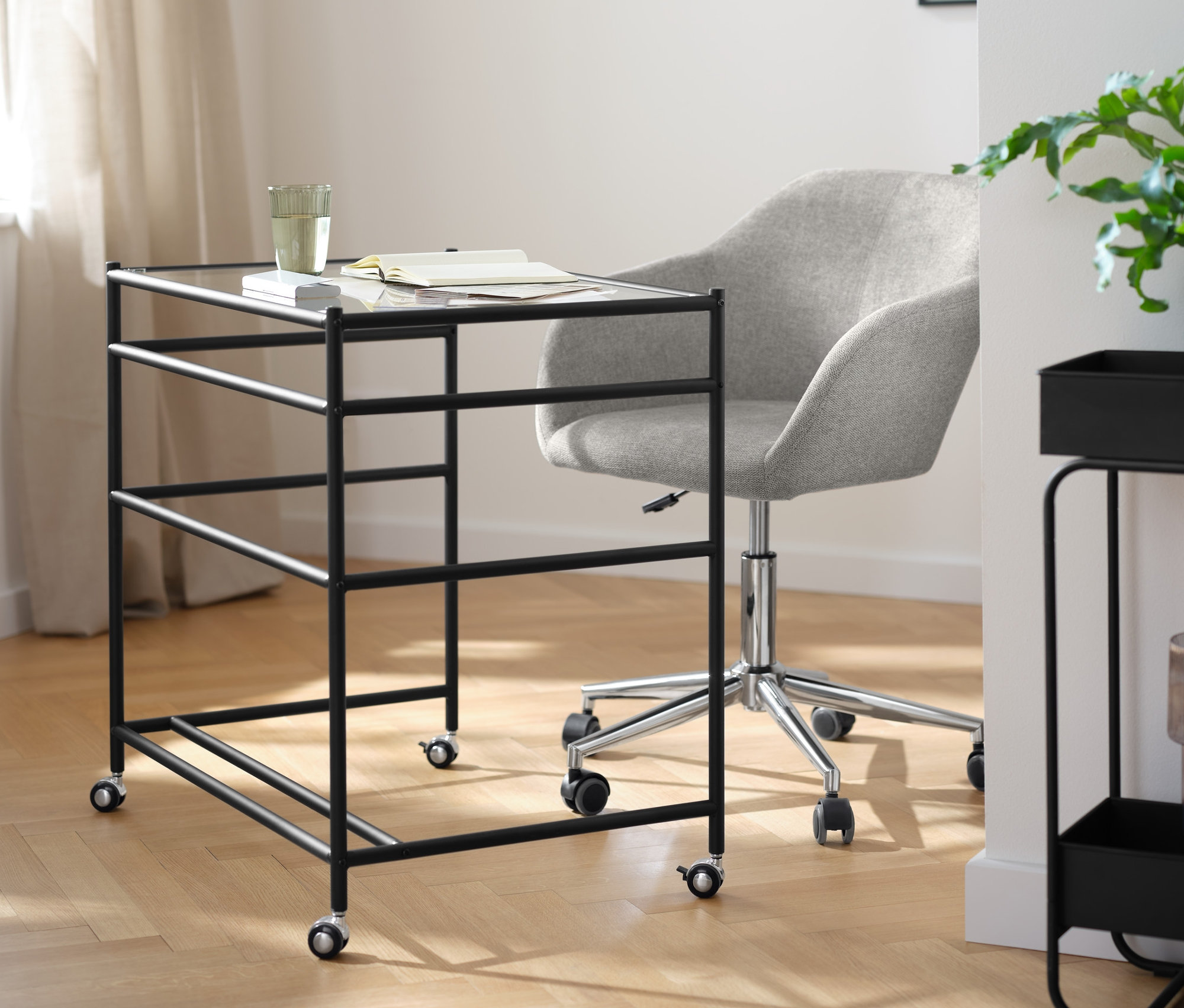 Egy görgős, üveglapos íróasztal és egy bézs forgószék látható a szobában.