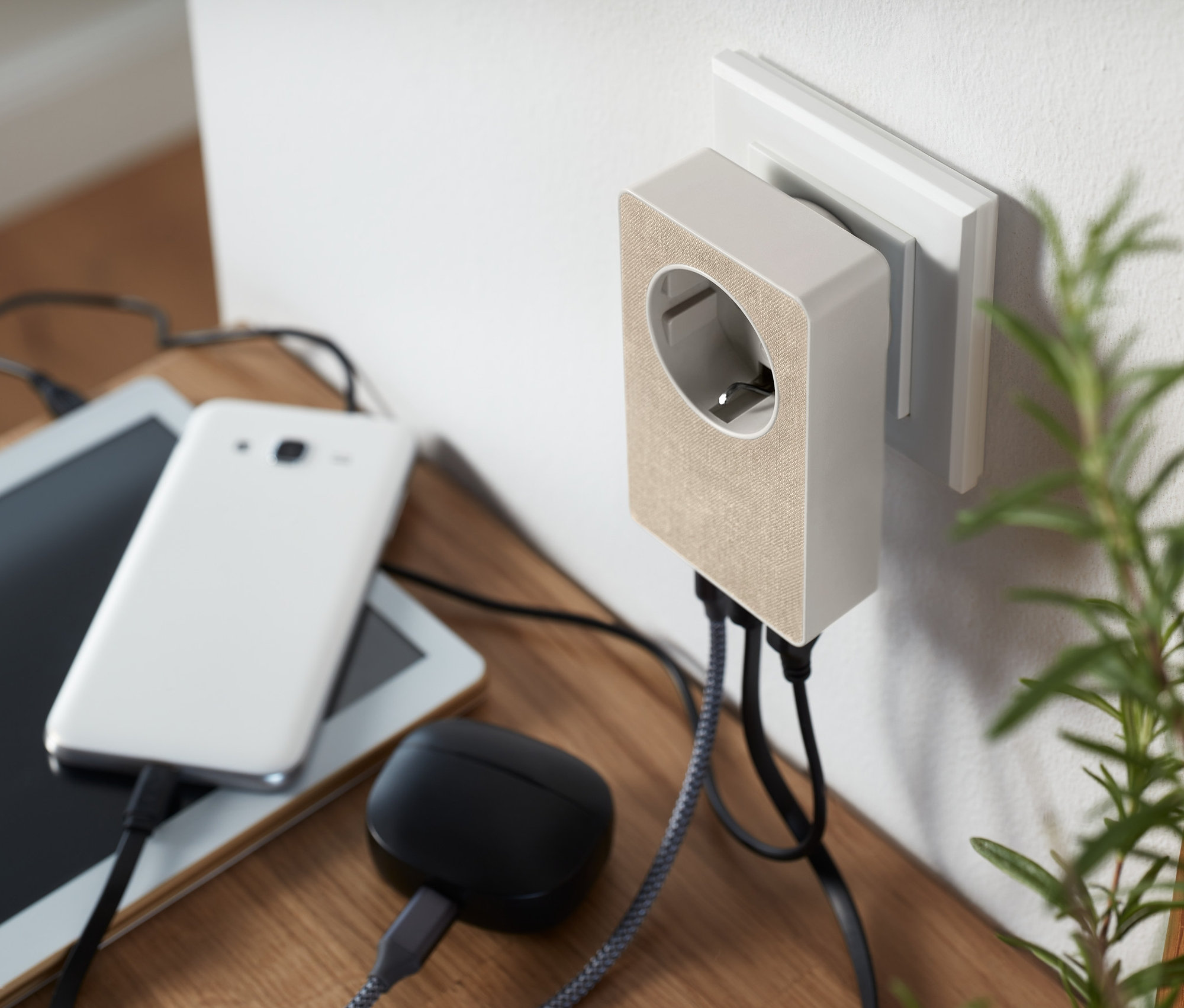 Egy 4 az 1-ben hálózati adapter, USB csatlakozik egy fali aljzathoz, telefon, tablet és fejhallgató van hozzá csatlakoztatva.