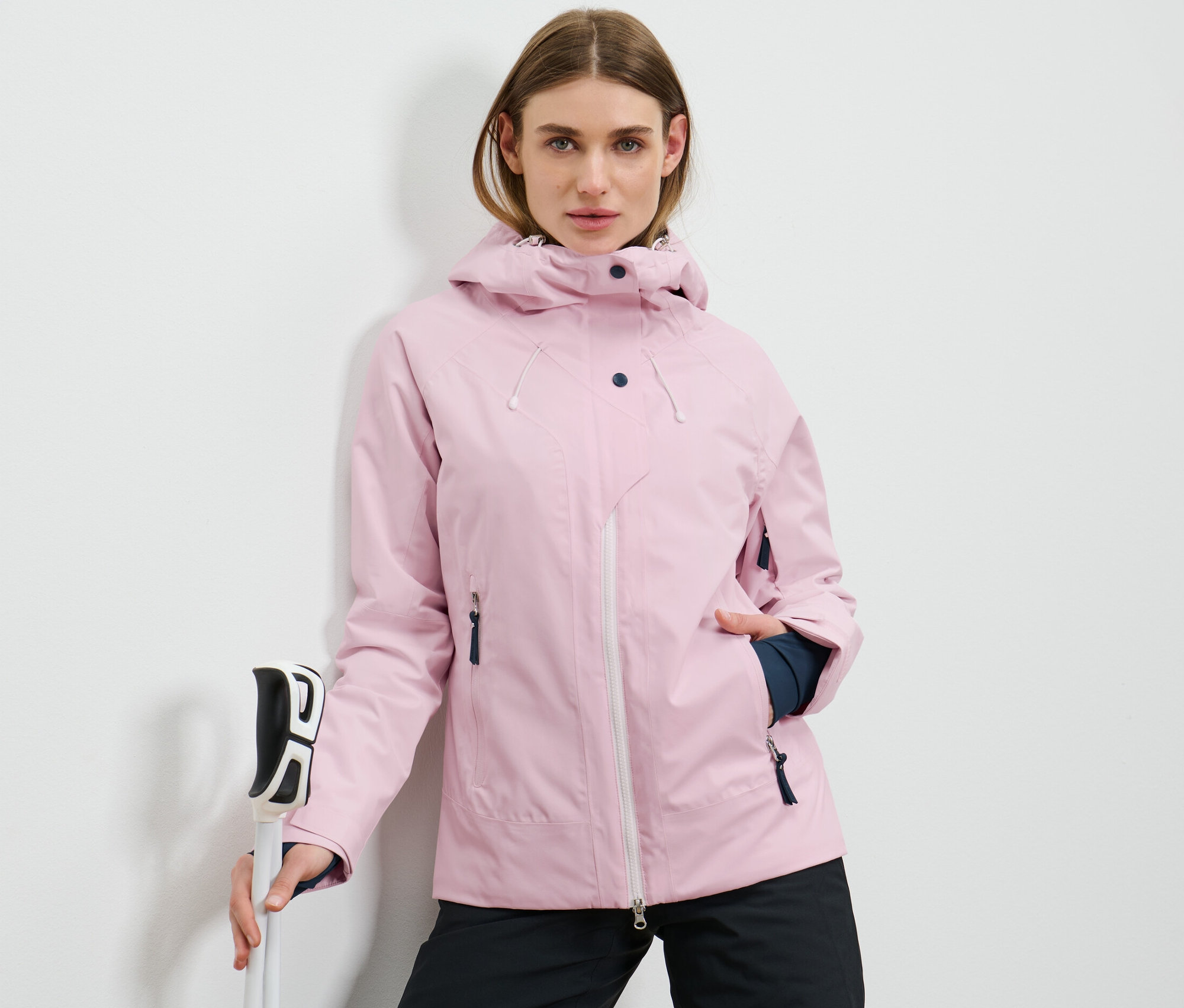 Nő síbotokat tart és rózsaszín síkabátot visel.
