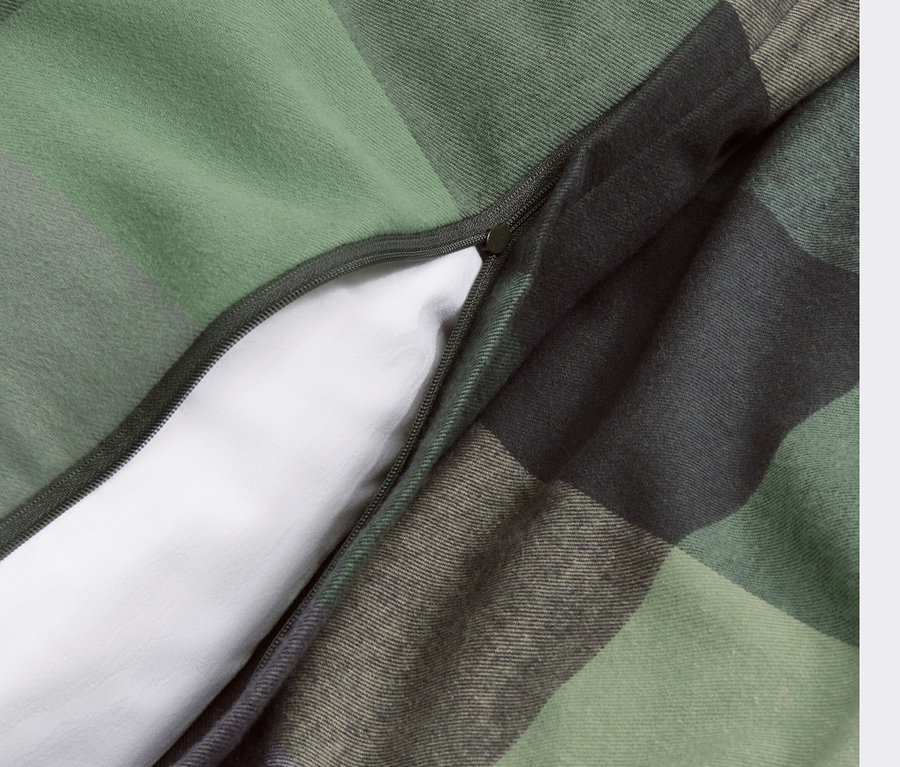 Egy flanel ágynemű részlete cipzárral és zöld kockás mintával.