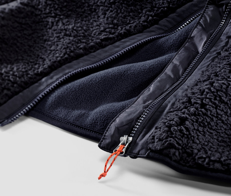 A sötétkék férfi plüssmellény cipzárjának közeli képe.