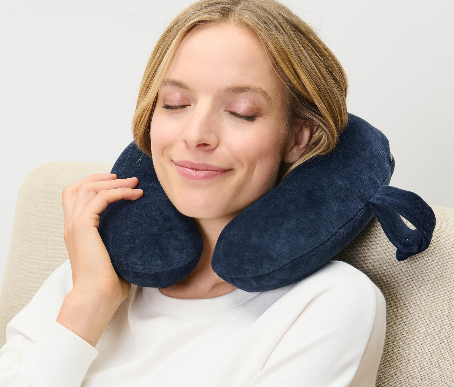 Nő ül egy székben, a nyakában sötétkék memóriahabos nyakpárna van.