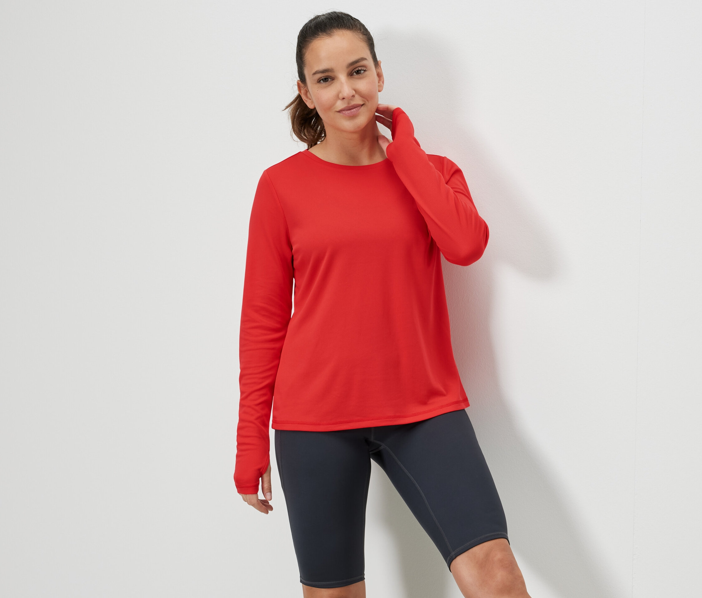 Nő pózol piros funkcionális felsőben.