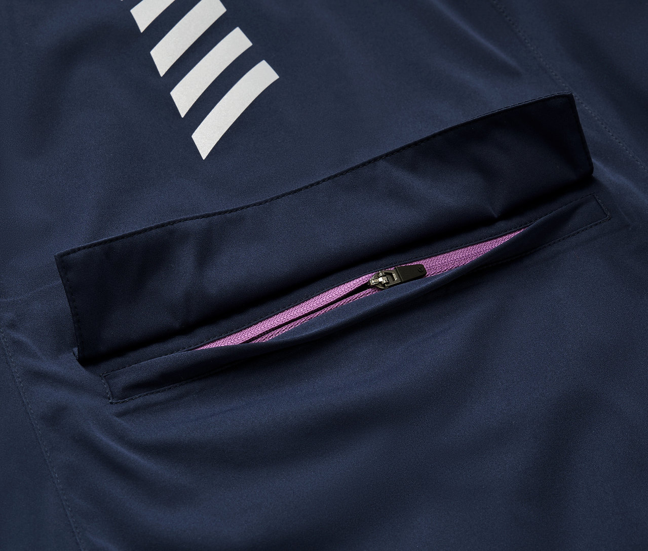 Egy sötétkék Rad-Regenjacke részlete fehér csíkokkal és lila cipzárral.