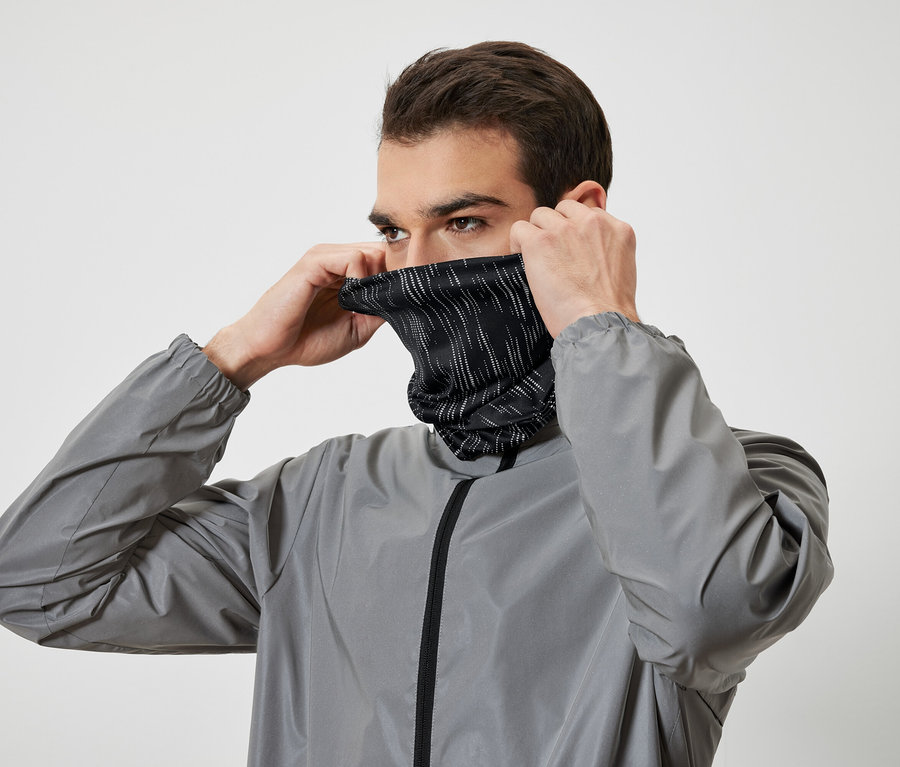 Egy férfi felvesz egy fekete, fehér csíkos nyakmelegítőt, és szürke kabátot visel.