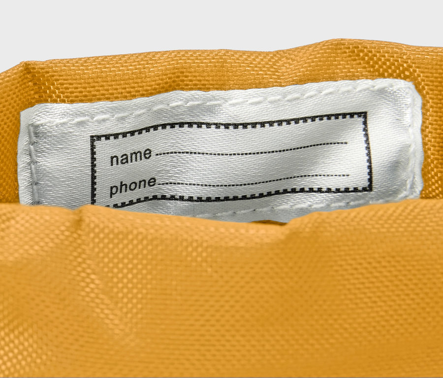 Sárga gyerek gumicsizma részlete fehér névtáblával.